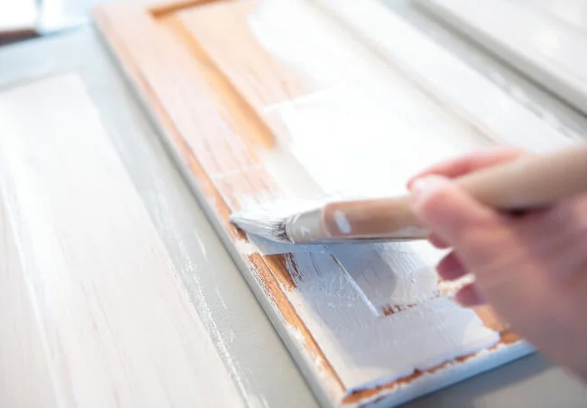 A professional painting cabinets with a brush